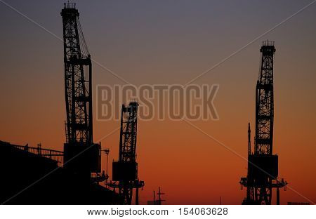 silhouette of three big cranes at sunset