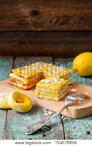 Homemade tasty layered lemon cake with tea and lemon curd on shabby wooden background with copyspace