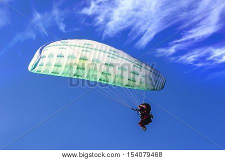 Tandem Paragliding on background of blue summer sky and white clouds