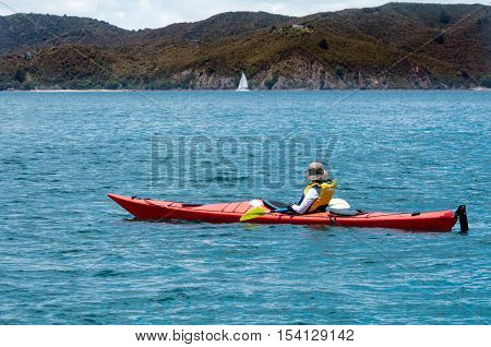 Woman rows a sea kayak in the bay of Island New Zealand. Very popular travel destination of NZ
