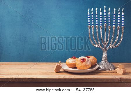Hanukkah holiday sufganiyot and menorah on wooden table over vintage background