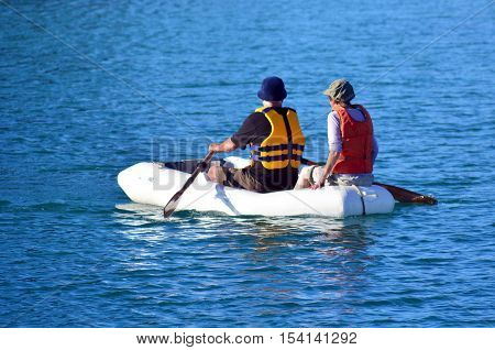 Couple rows a rubber inflatable dinghy boat.
