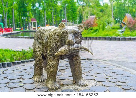 KHARKOV UKRAINE - MAY 20 2016: The bronze sculpture of a bear with a fish next to the pond in Gorky Park of Kharkov  on May 20 in Kharkov.