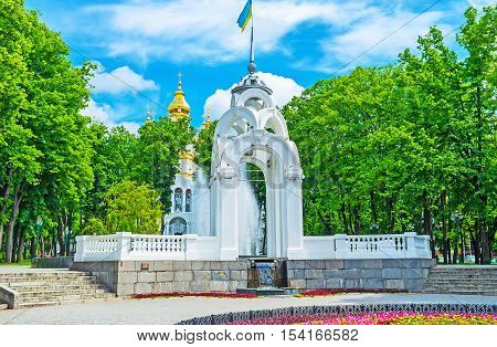 The scenic white alcove in Victory Square with the Mirror Fountain and bright gilt domes of the Church of Holy Myrrh-Bearers on the background Kharkov Ukraine.