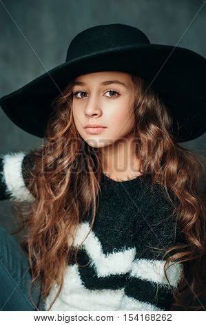 Portrait of beautiful fashion small girl in hat on vintage background
