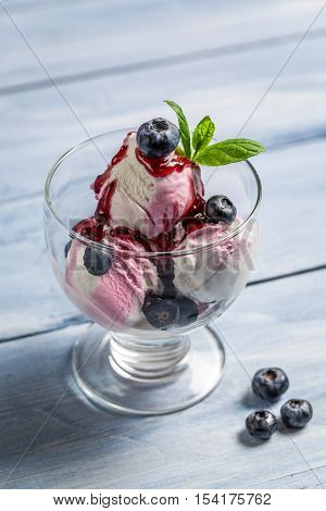 Bowl with blueberry ice cream on old wooden table