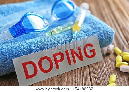 Sports equipment, word Doping and syringe on wooden background