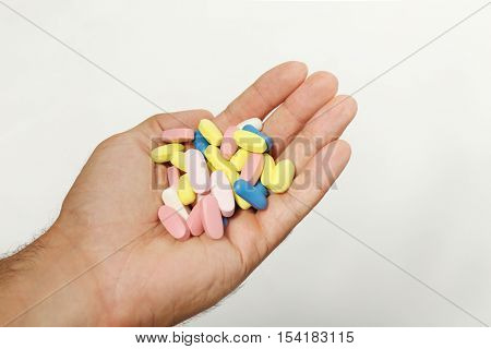 Male hand holding drugs on color background