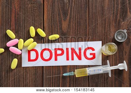 Word Doping and syringe on wooden background