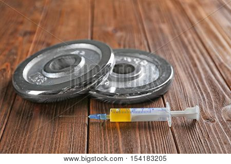 Weight disks and syringe on wooden background