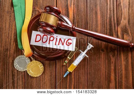 Gavel, word Doping and syringe on wooden background