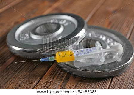 Weight disks and syringe on wooden background