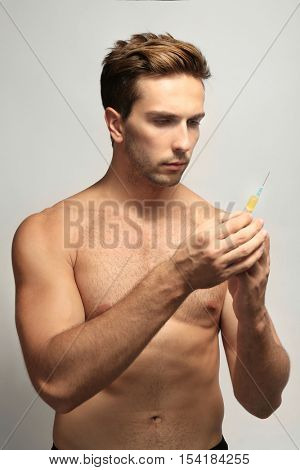Muscular man holding syringe on white background