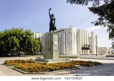 Kurgan, Russia - August 19, 2016: The monument of Natasha Argentovskaya - a participant of the revolutionary struggle in the city of Kurgan, Russia. Kurgan Philharmonic in the background.