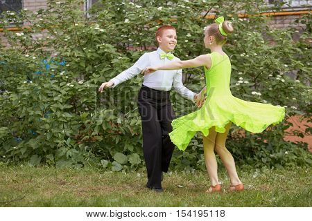 Little boy and girl dance ballroom dance outdoor at grassy lawn.