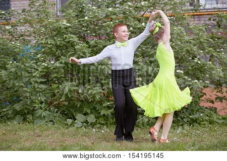 Little boy and girl dance ballroom dance outdoor at grassy lawn.