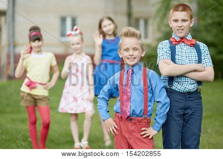 Two smiling boys at foreground, three girls behind them out of focus.