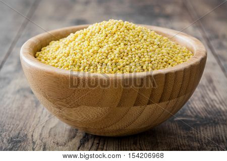 Organic millet seeds in wooden bowl on wooden table