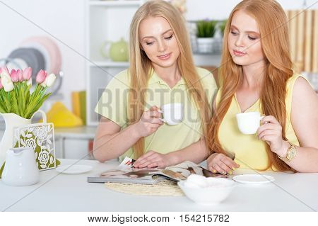 portrait of girls  drinking coffee or tea  with magazine at home