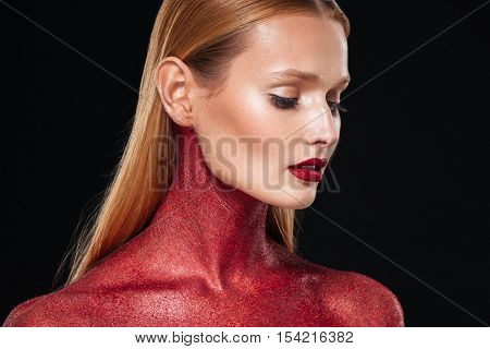 Woman with red bodypainting in profile. Close up portrain. Looking down