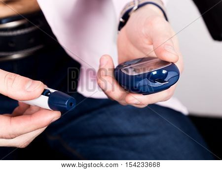 Dependent first type diabetes patient. Measuring glucose level blood test using ultra mini glucometer and small drop of blood from finger and test strips.