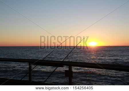 a gorgeous sunset with some fishing rods take at the Belgian coast near Blankenberge