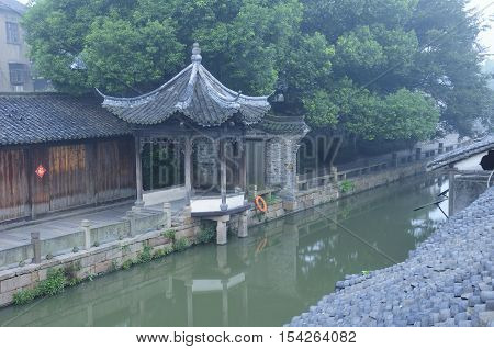 Weathered buildings lining the water canals in tongxiang wuzhen scenic town east view in Zhejiang province China in the early morning mist the character Fu meaning blessing on a sign.