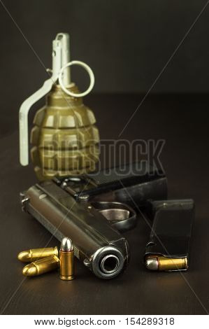 Pistol and a grenade on the table. Preparing for battle. Handgun with ammunition on a dark wooden table. Sales of weapons and ammunition. Advertising on ammunition. New gun and ammunition.