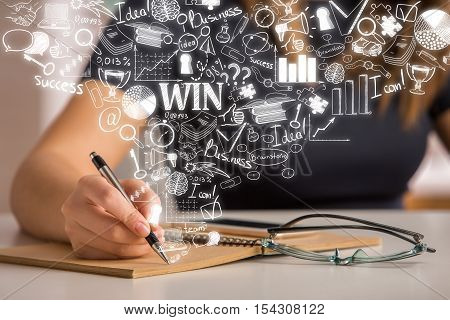 Female hand writing in spiral notepad with abstract business sketch