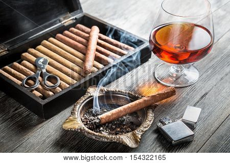 Aroma of cognac and cigar fuming on wooden table