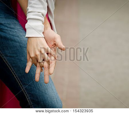 A young couple holding hands outdoors. Shallow depth of field