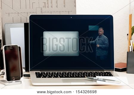 PARIS FRANCE - OCT 28 2016: Apple Computers website on new MacBook Pro Retina with OLED Touch bar in geek creative room showcasing Apple Keynote Thilip Schiller talking about old laptop