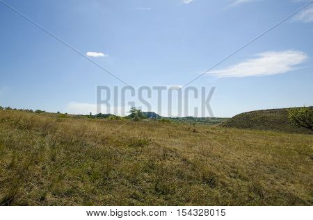 The landscape of rolling hills against the blue sky with clouds.