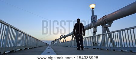 A man walks over the Gold Coast Pier during sunrise at the Spit in Queensland Australia.