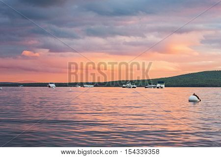 Pink and Orange Sunset on Water with Boats and Mountains