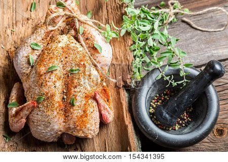 Raw chicken with herbs ready to cook on wooden table