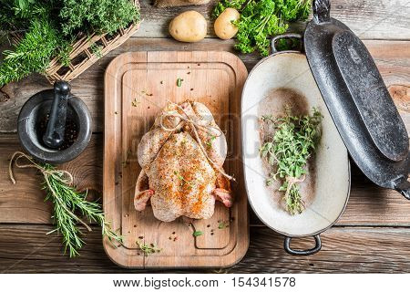 Preparation for roasting chicken with herbs on wooden table