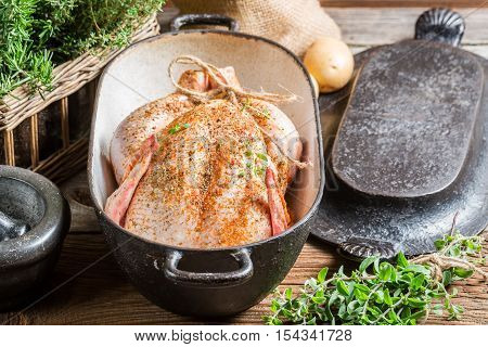 Closeup of spiced chicken before roasting on wooden table