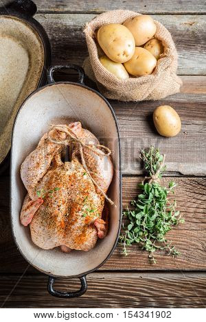 Preparing chicken for cooking with spices on wooden table