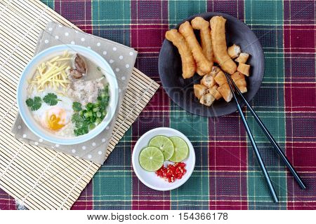 Rice porridge with mined pork and chicken lever served with side dish as Patongko (deep-fried dough stick) and spicy sour filling.