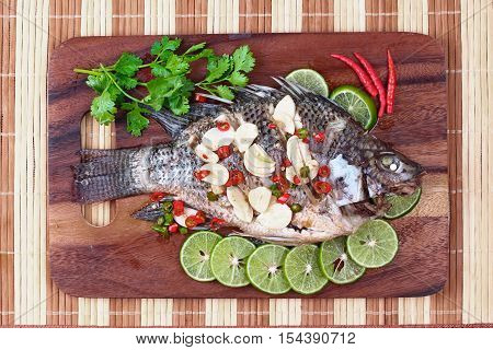 Tilapia fish streamed with lemon topped spicy sour ginger and chili on butcher served. (Call Pla Nil Nuang Manoaw in Thai)