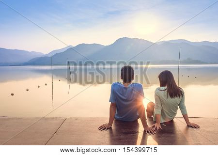 A couple on the wooden port at a lake on sunset