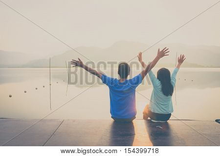 A couple on the wooden port at a lake on sunset