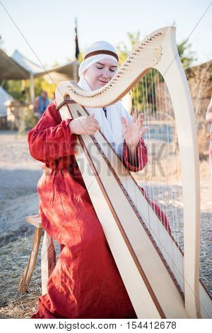 SEVASTOPOL, RUSSIA - SEPTEMBER 11, 2016: Woman dressed in vintage clothes plays harp on Crimean Military Historical festival