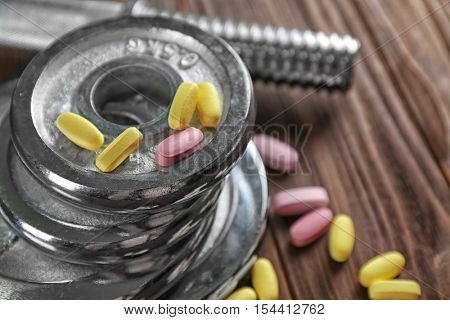 Weight disks and drugs on wooden background