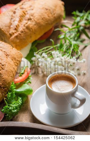 Coffee and sandwich for breakfast on wooden table