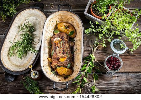 Roasted venison with herbs and vegetables on wooden table