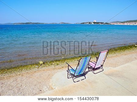 Two deckchairs on a pebble beach in Vodice in Croatia.