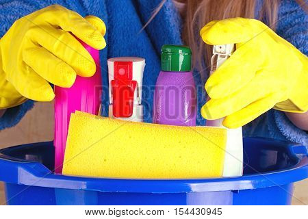 close-up of caucasian woman holdinh basin with cleaning supplies
