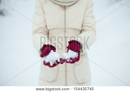 winter girl throwing snowball at camera smiling happy having fun outdoors on snowing winter day playing in snow. Cute playful multicultural Asian Caucasian young woman outdoor enjoying first snow.